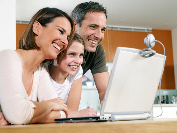 Mother Father and Daughter (9-11) Smiling at Laptop Computer